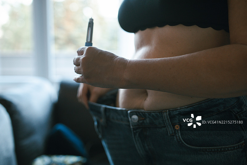 糖尿病治疗的真实描绘：女性在家中自我注射胰岛素 - 医疗准确性，笔式注射器图片素材