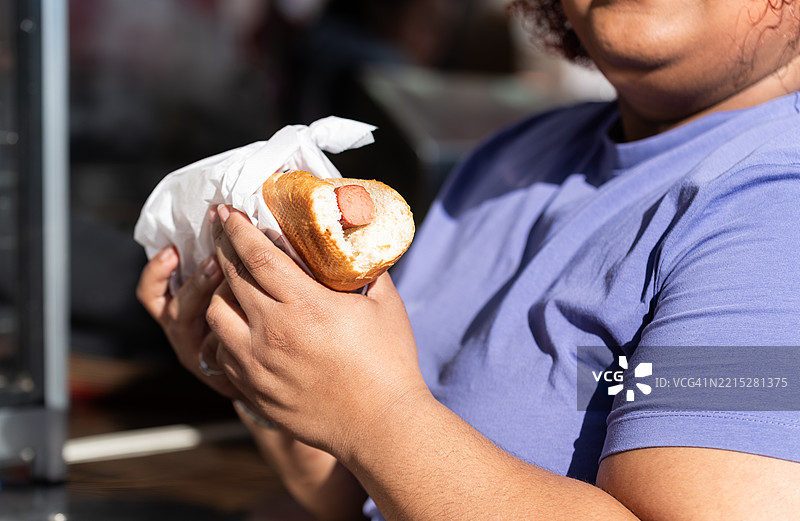 女人在户外食品摊享用热狗图片素材