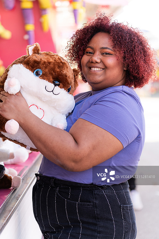 女人在游乐场摊位赢得一个毛绒玩具图片素材