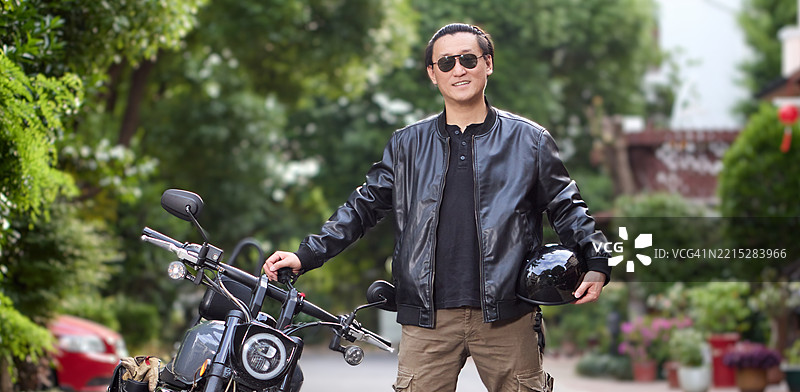 穿着皮夹克的骑士站在他的摩托车旁图片素材