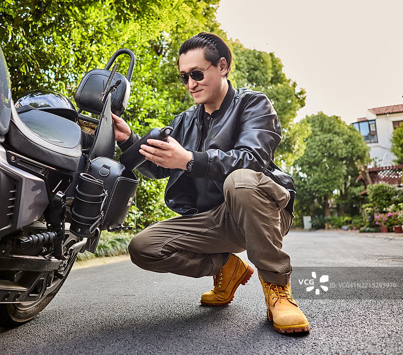 骑士在乡间小路上为摩托车打包装备图片素材