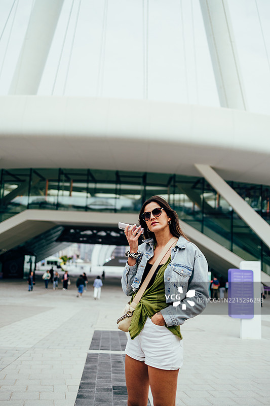 时尚年轻女性在现代城市环境中使用智能手机图片素材