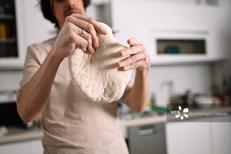 男人在家厨房里揉制比萨或面包的面团图片素材