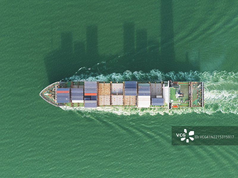 航拍视角的集装箱货船，满载集装箱，从商业港口的码头出发，适用于商业物流、进出口、航运或货物运输。图片素材