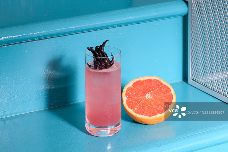 粉色鸽子鸡尾酒与葡萄柚和洛神花放在蓝色楼梯上图片素材