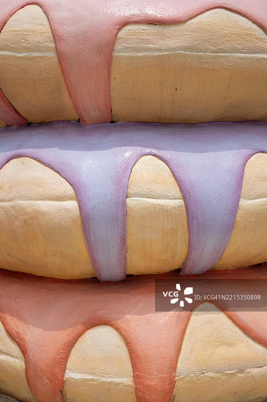 一个大型蛋糕雕像，上面装饰着粉色和紫色的糖霜图片素材