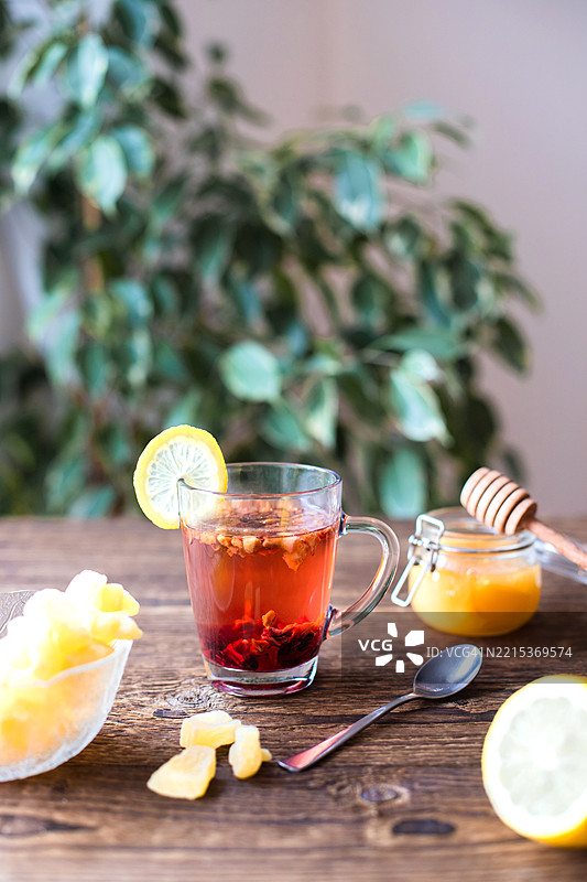 木桌上冒着热气的草本茶，配有蜂蜜和蜜饯姜。图片素材