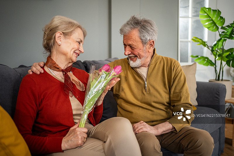 老年男子在家里给妻子送花图片素材