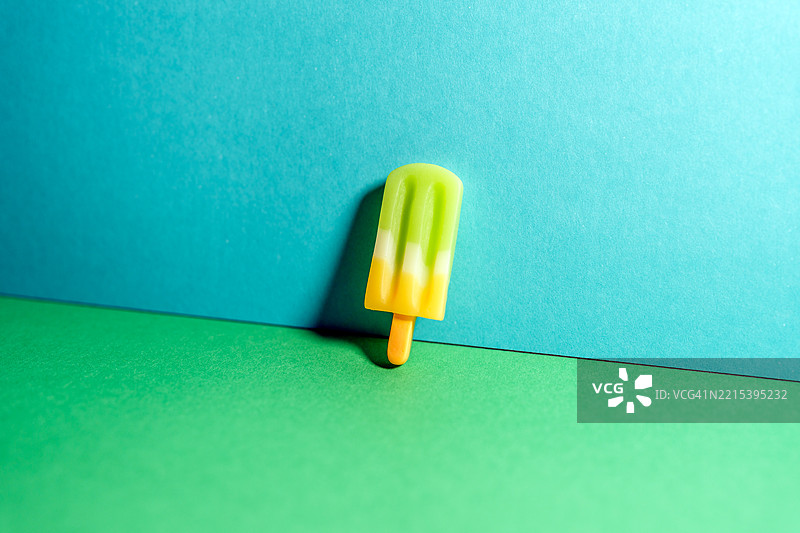 色彩缤纷的冰棒矗立在生机勃勃的绿色表面上，背景为蓝色。图片素材