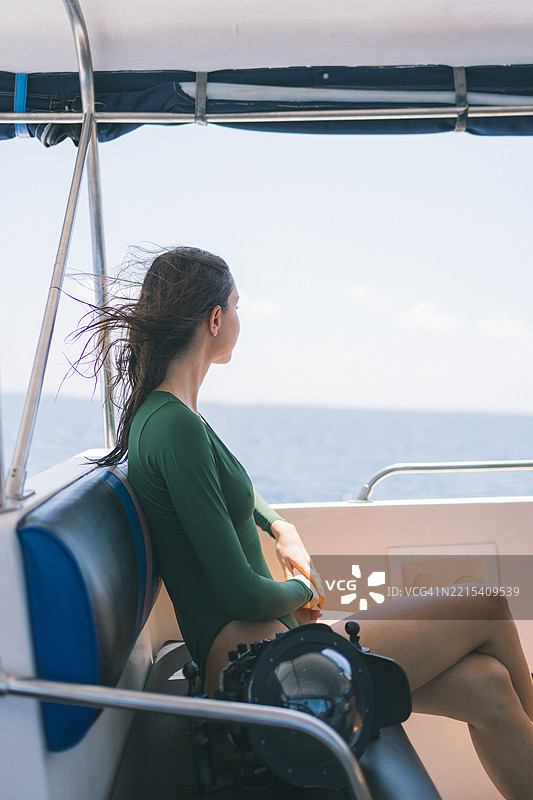 年轻女性在游艇上放松，手持望远镜图片素材