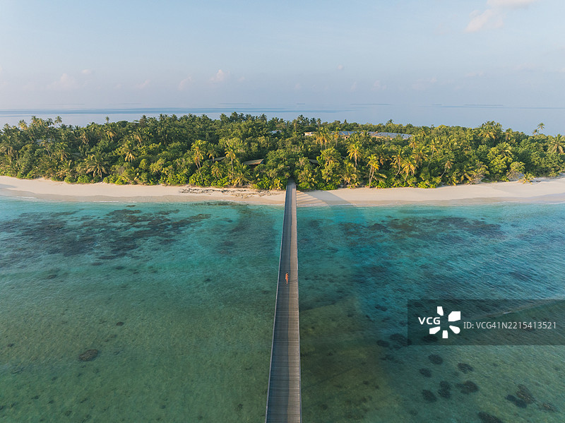 年轻女性在热带泻湖上的木栈道上做瑜伽动作的鸟瞰图图片素材