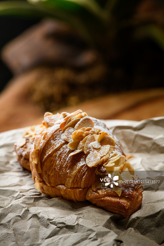 撒上糖粉的杏仁可颂面包放在烘焙纸上图片素材