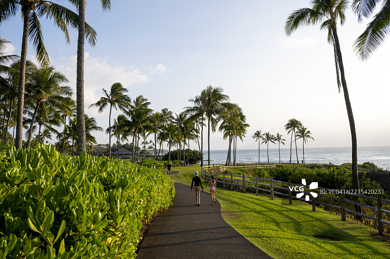 年轻女孩在海岸线的铺装小径上徒步旅行图片素材