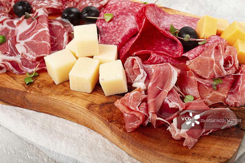 各种切片肉类开胃菜，意大利火腿、萨拉米香肠和火腿，搭配奶酪和橄榄，放在木板上，早餐，俯视图，特写，无人。图片素材