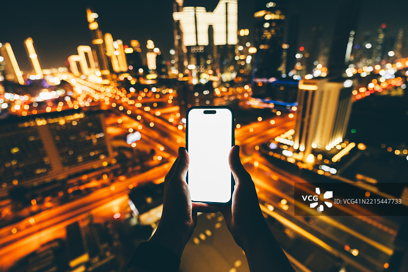 手握手机俯瞰城市。图片素材