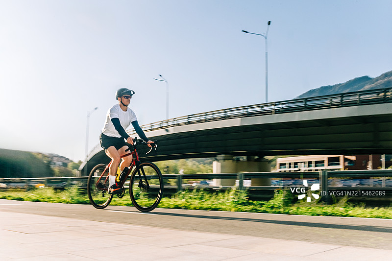 男子在高速公路立交桥附近的自行车道上骑行图片素材