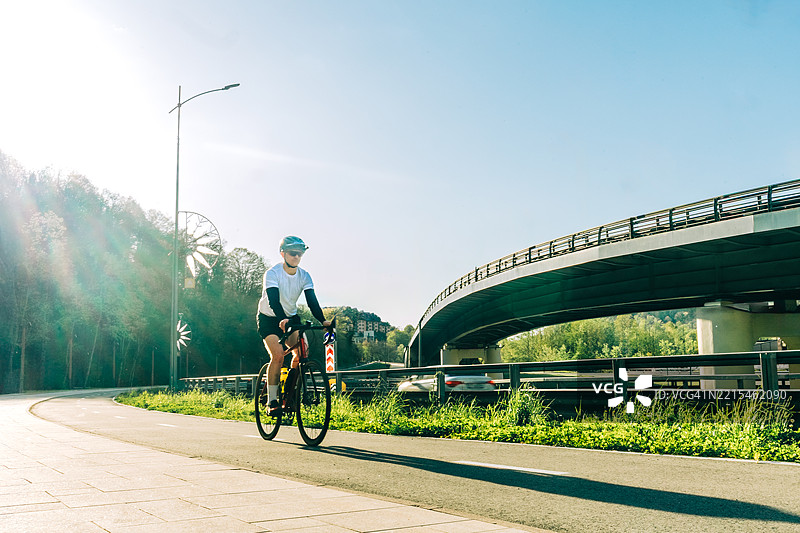 男子在高速公路立交桥附近的自行车道上骑行图片素材