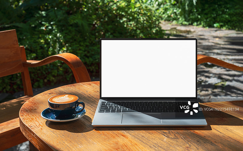 咖啡馆背景下桌子上的笔记本电脑空白屏幕。咖啡店桌子上的空白屏幕笔记本电脑，背景模糊。图片素材