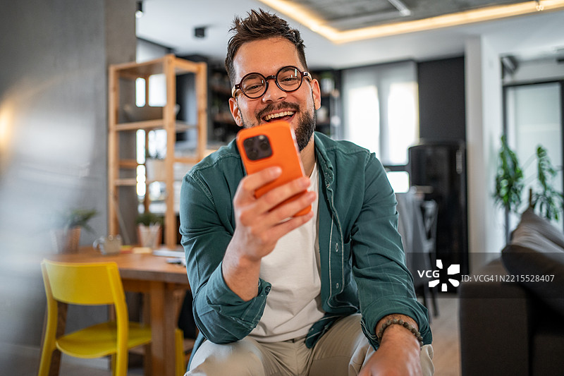 快乐的自由职业者在家办公时用智能手机享受成功图片素材