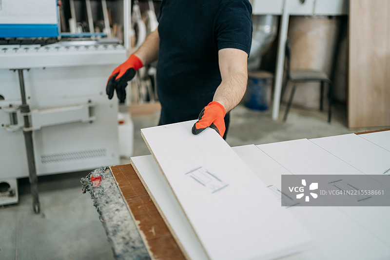 木匠在工作室里捡起白色木板图片素材