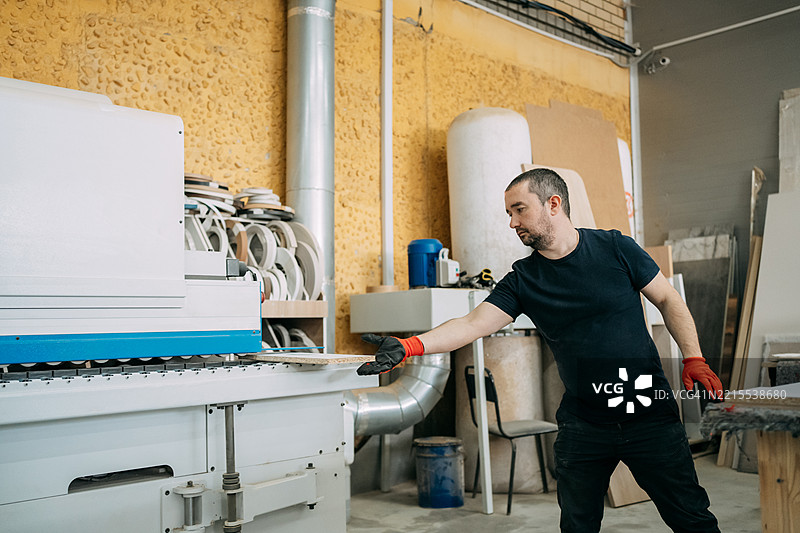 在家具厂中，木匠正在使用封边机。图片素材