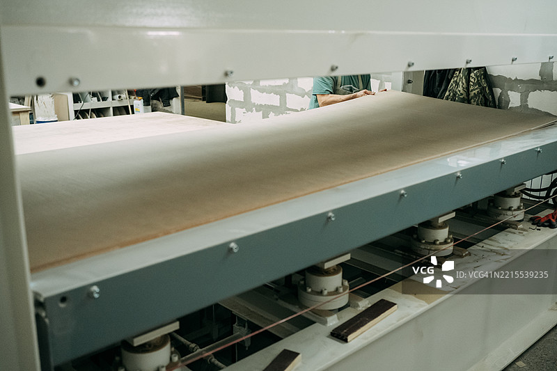 木匠将木板放入液压 laminating 压机中图片素材
