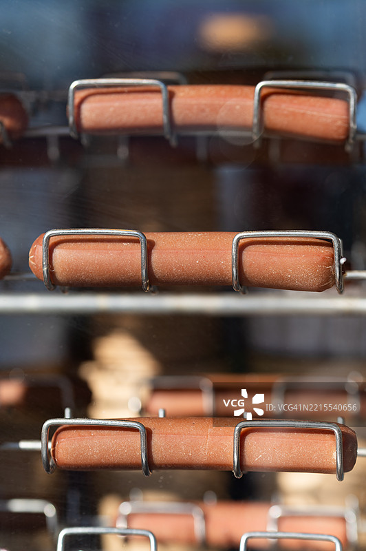 户外食品摊位上旋转烤架上加热的热狗图片素材