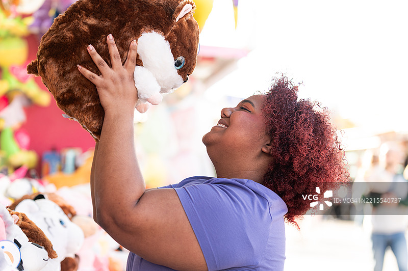 女人在集市上抱着一个毛绒玩具图片素材