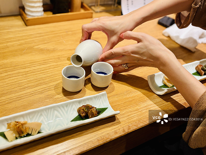 一位女性正在倒日本清酒。图片素材