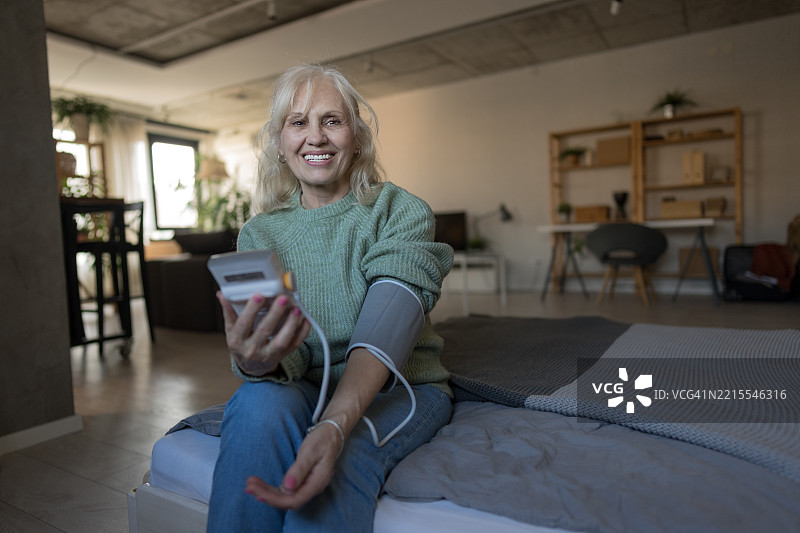 卧室里老年女性正在测量血压图片素材
