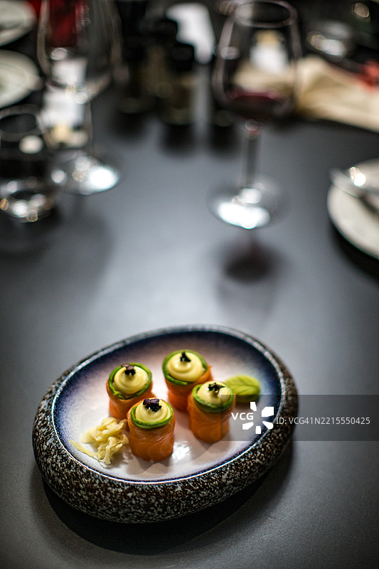 夜晚奢华餐厅黑色桌子上的精致寿司菜肴图片素材