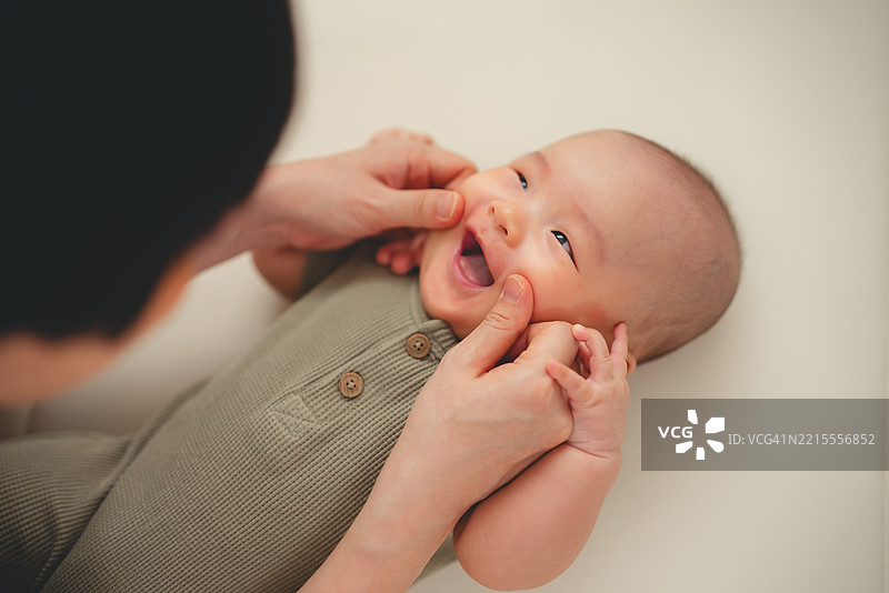 亚洲母亲在家中与婴儿在游戏围栏里玩耍。图片素材