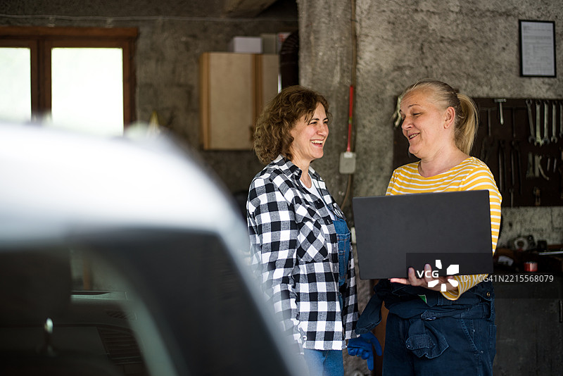 两名汽车维修工一起合作，使用笔记本电脑进行汽车检查图片素材