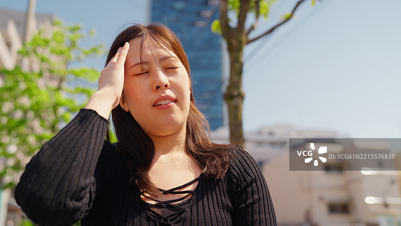 女人在城市的阳光明媚的炎热天气中感到过热图片素材