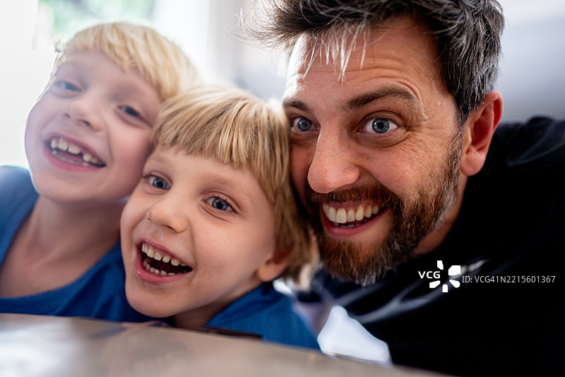 快乐的父亲和儿子们一起享受高质量的亲子时光，使用移动设备。图片素材