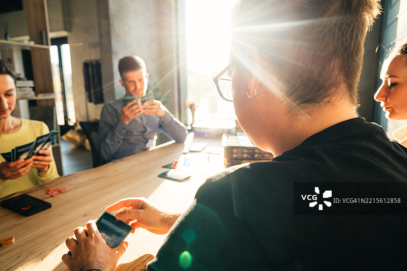 朋友们在阳光明媚的房间里一起享受纸牌游戏图片素材