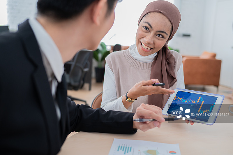 亚洲年轻建筑师在办公室讨论项目，使用数字平板电脑图片素材