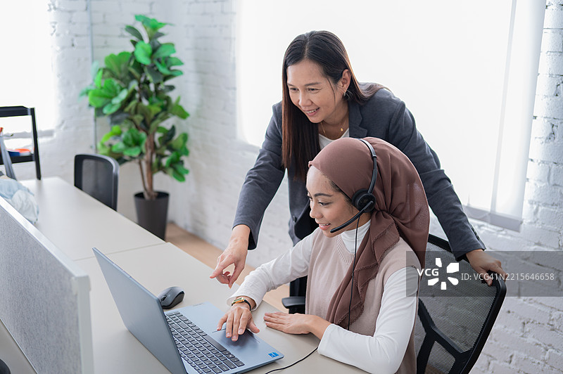 亚洲女商人站着检查员工的工作进展图片素材