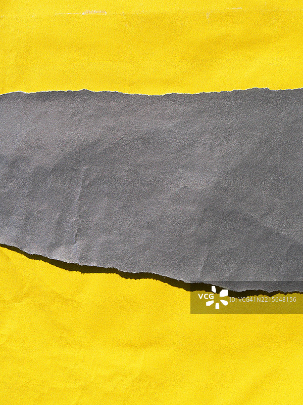 撕裂的灰色纸张特写,背景为皱褶的黄色纸张。阳光。自然色彩。全画幅 4:3 巴黎,法国。图片素材