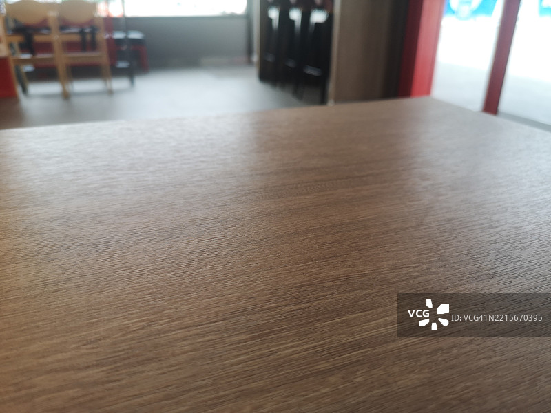 深棕色木质桌子，背景为模糊的咖啡店环境图片素材