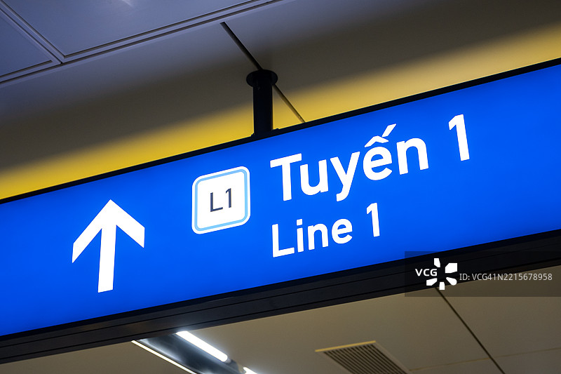 一个清晰的指示牌指向地铁1号线，引导乘客前往附近的车站入口，越南胡志明市。图片素材