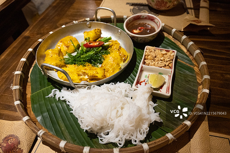 一盘查卡拉旺菜肴，特色是烤黄姜蛇头鱼，配有面条和新鲜香草，越南河内。图片素材