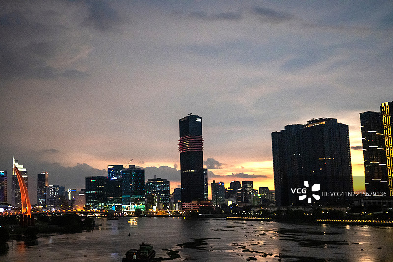 全景视角捕捉到现代摩天大楼在西贡河中的倒影，沐浴在日落的光辉中，越南胡志明市。图片素材