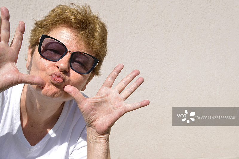 一位60岁女性在镜头前开玩笑的肖像图片素材