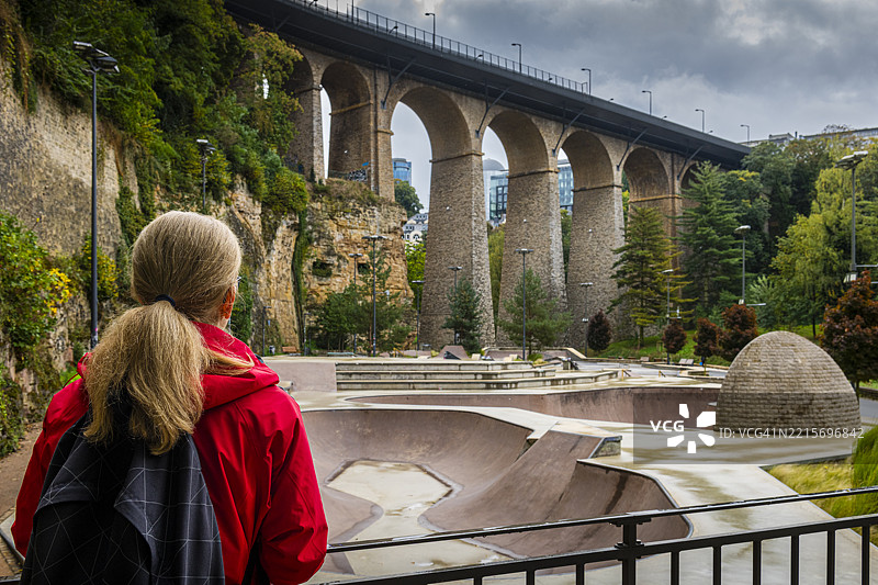一位女性在卢森堡的滑板公园前凝视着一座古老的渡槽。图片素材