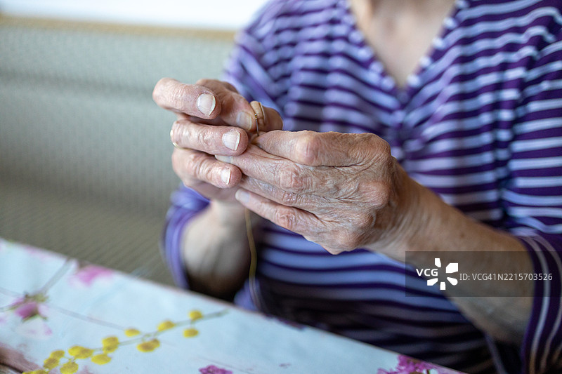特写镜头：老年女性的手试图将线穿入针眼中图片素材