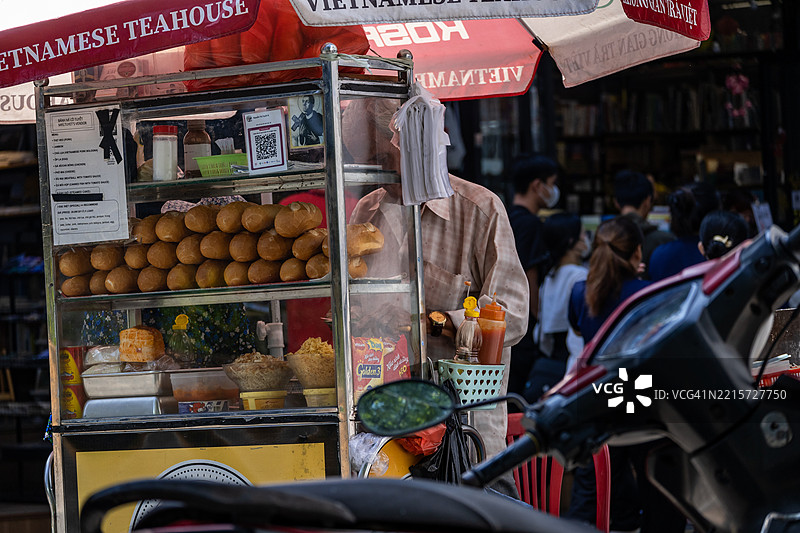 越南胡志明市的一个当地街头小吃摊，摊位上摆满了法棍面包，正在用自行车制作越南法式三明治。图片素材