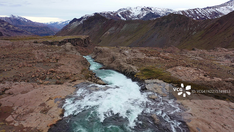 安第斯山脉中智利和阿根廷边界的毛尔河及瀑布的无人机视角，湛蓝的水流映衬着南美的山脉风光。图片素材