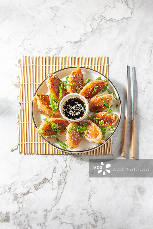 美味的亚洲饺子（锅贴）配酱油蘸料，盛放在盘子里图片素材