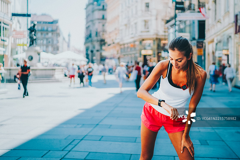 女人在繁忙的城市街道上跑步后喘息图片素材